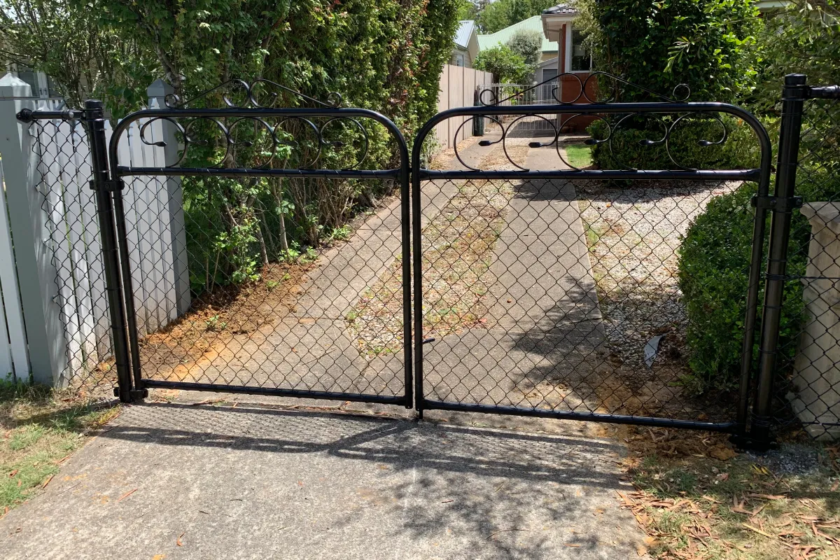 Ornate black steel double driveway gate with chain wire infill